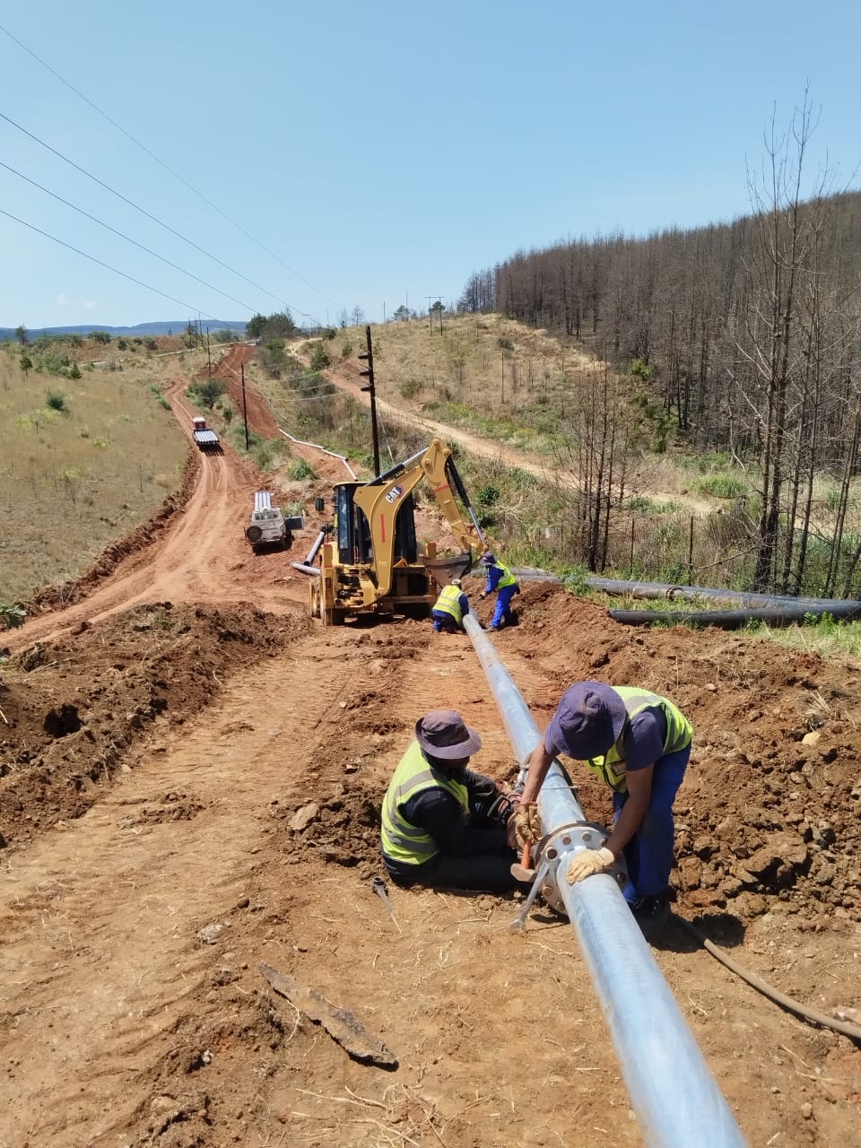 Wetpipe technicians assembling a flanged slurry pipeline joint on a hillside route