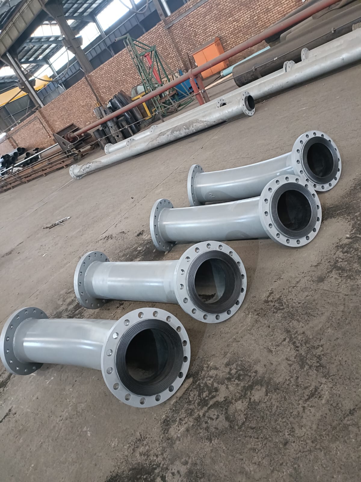 Lined steel slurry pipe bends with flanged ends in the Wetpipe workshop
